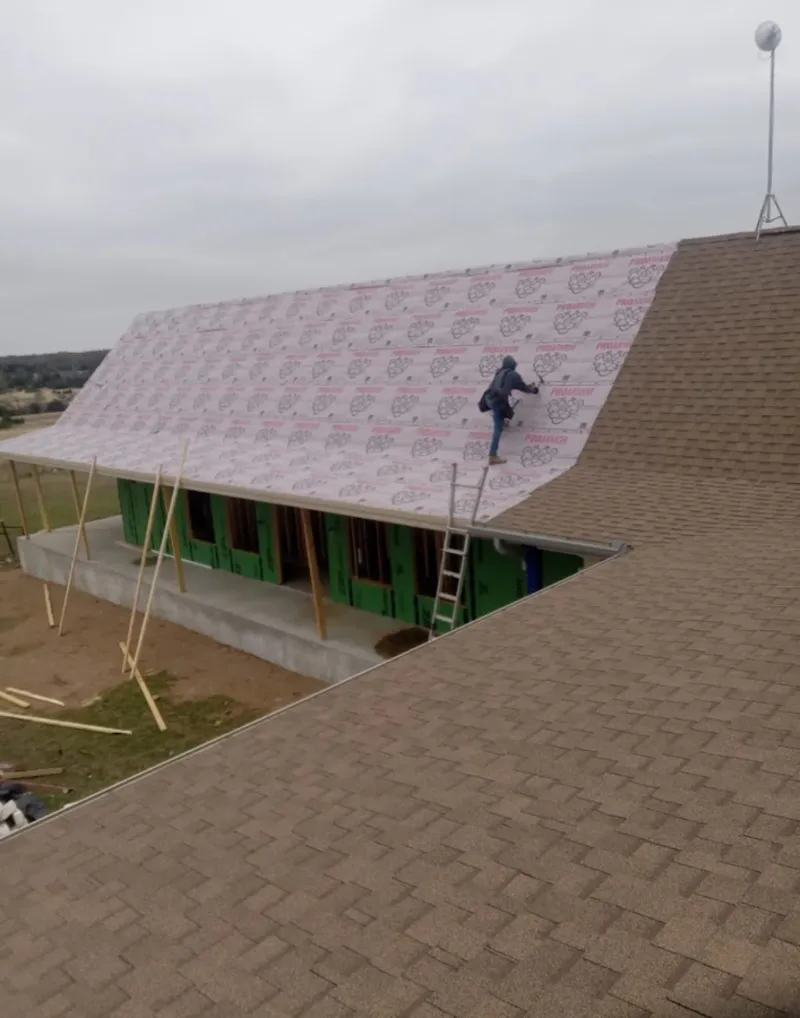 Worker preparing underlayment for a metal roof installation in Arden-Arcade